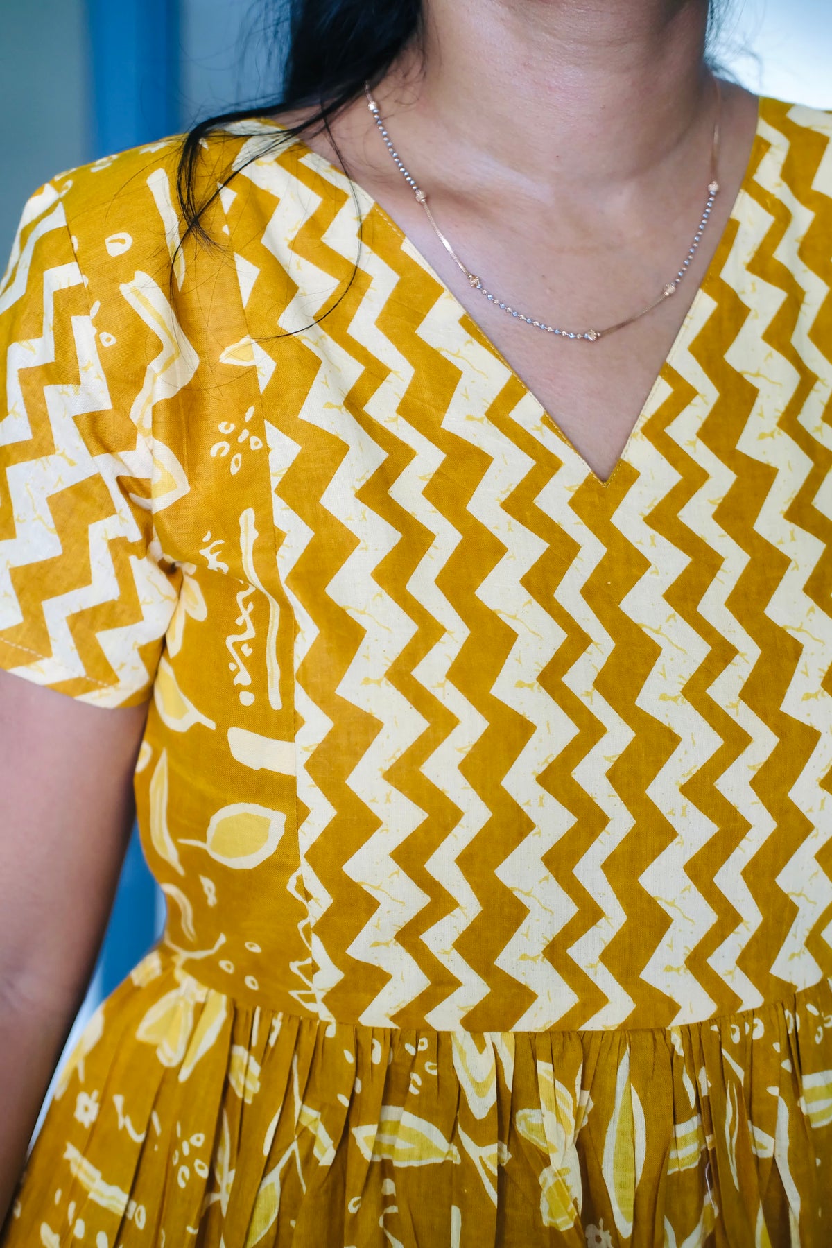 Close-up of the V-neckline and chevron pattern on the mustard yellow feeding nighty cotton fabric.