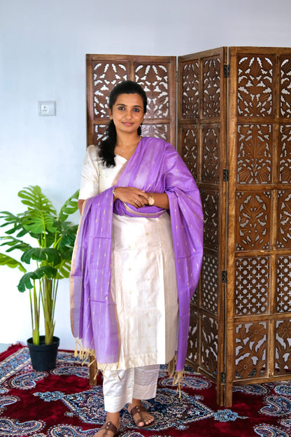 off white suit set with a V-neckline and gold zari woven details paired with a contrasting purple dupatta