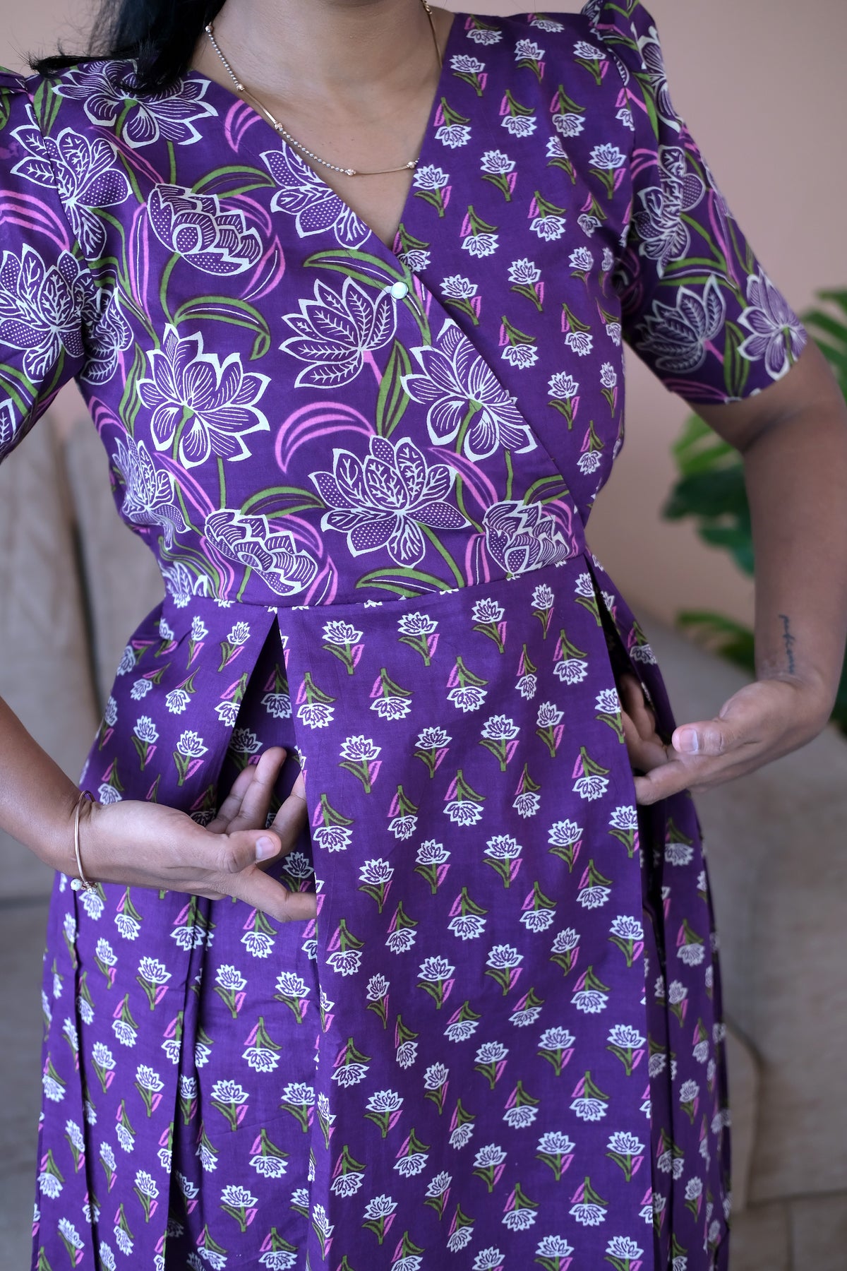 Close-up of the box pleats, side pockets, and floral print on the violet cotton midi nighty.