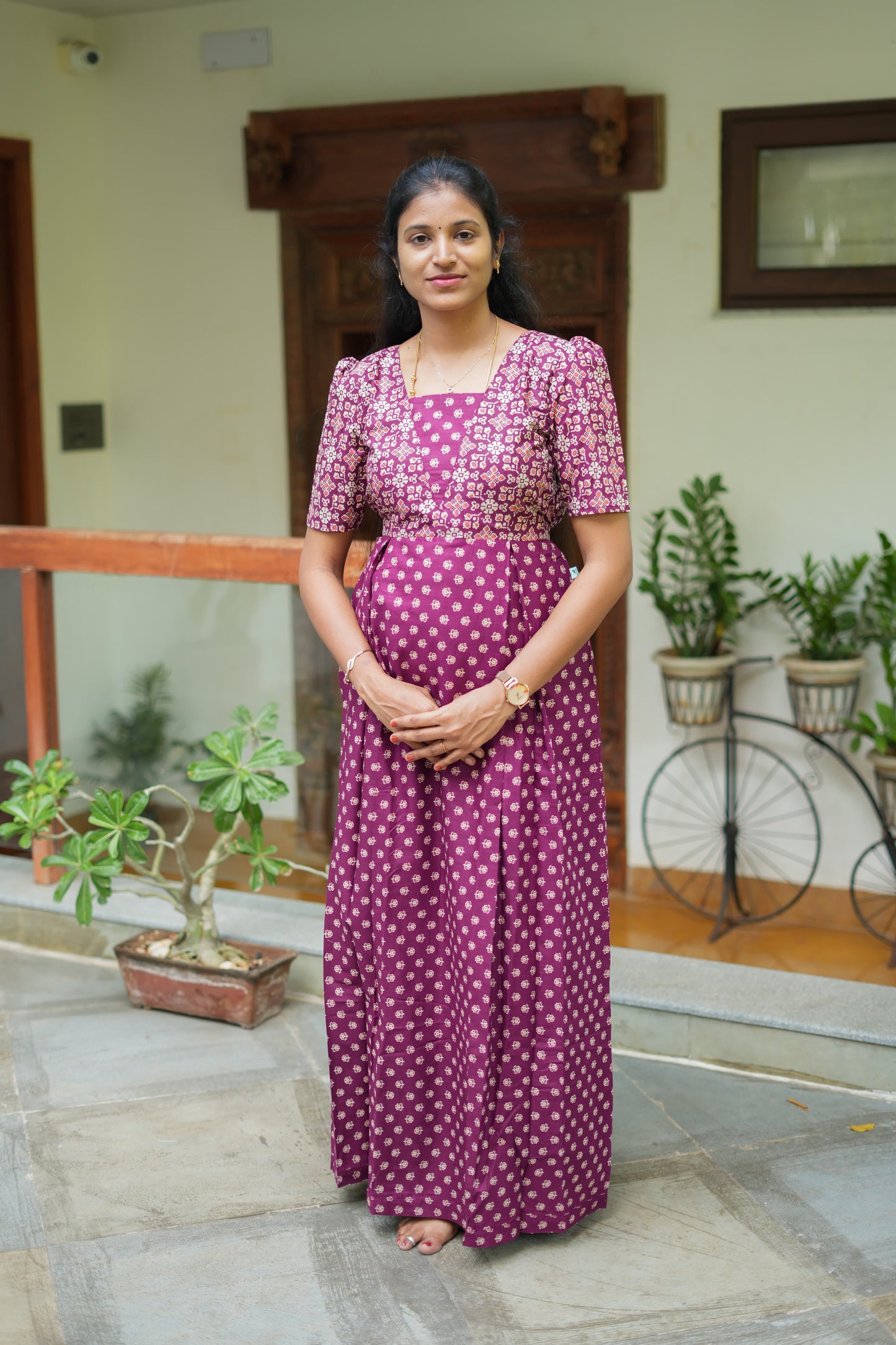 A woman wearing the Nisha dark purple cotton maxi nighty with a square neck and puff sleeves.