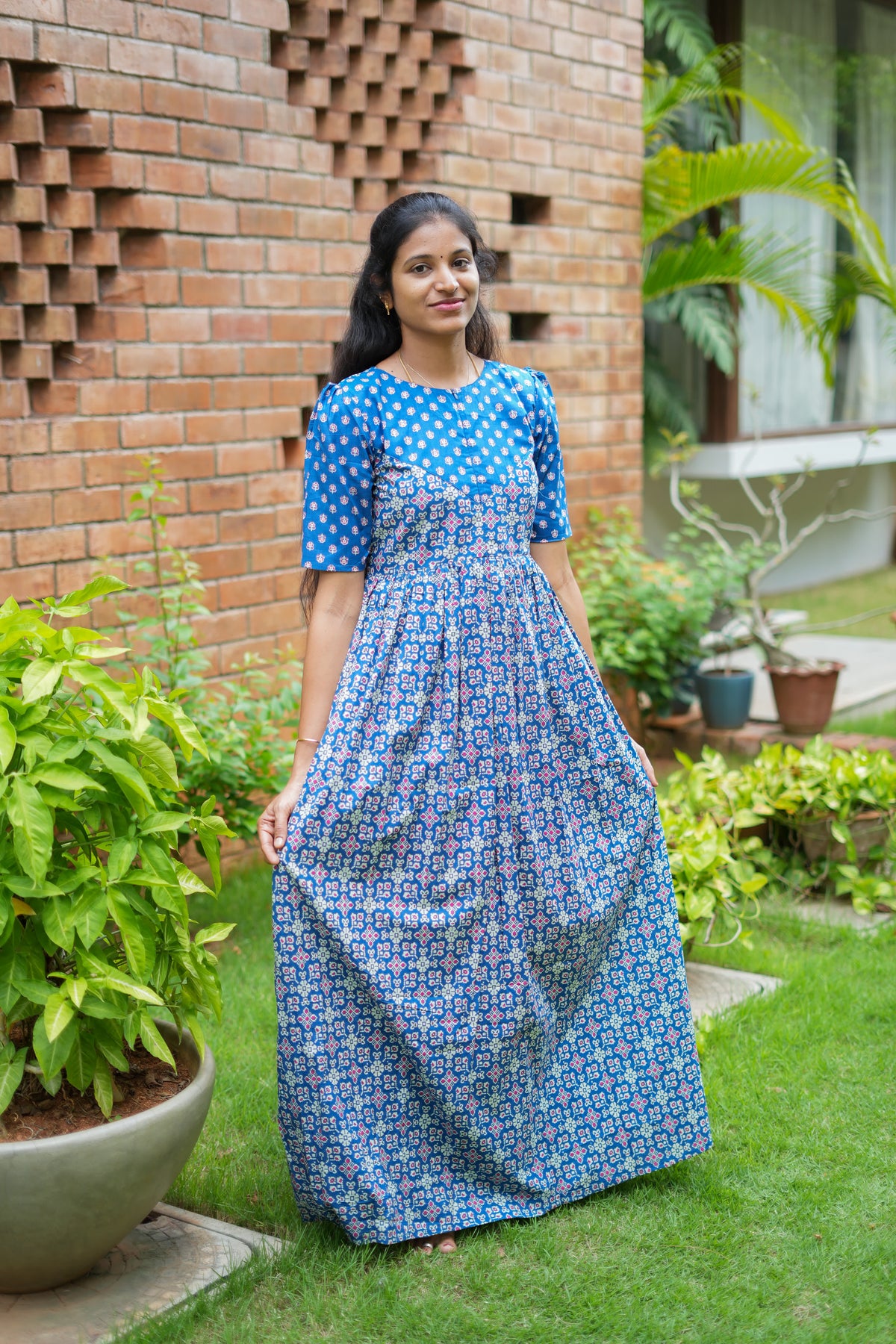 A woman wearing a royal blue ladies cotton nighty standing in a garden