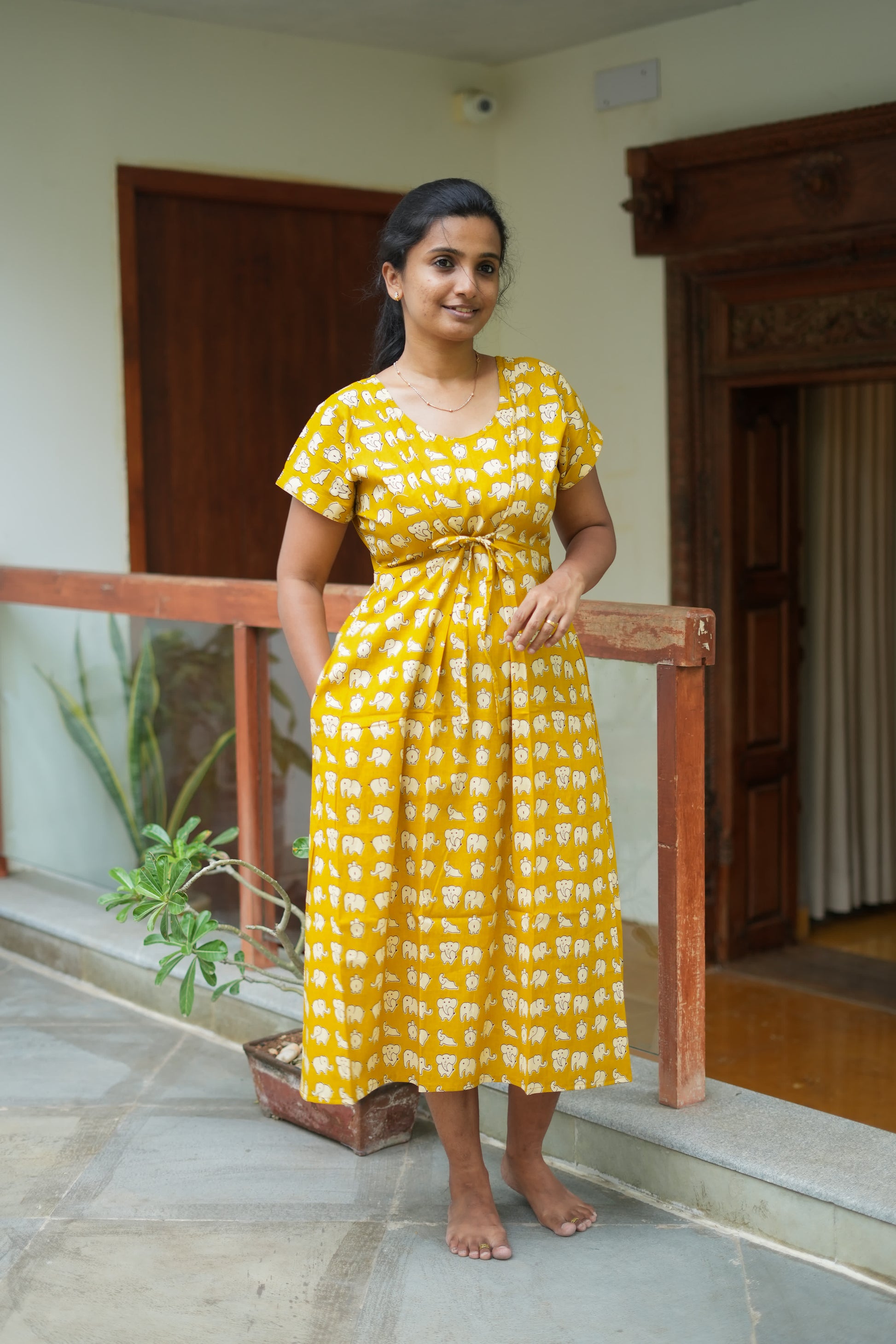 Mustard yellow cotton nighty for women featuring a white elephant print, short sleeves, and an adjustable front waist tie.