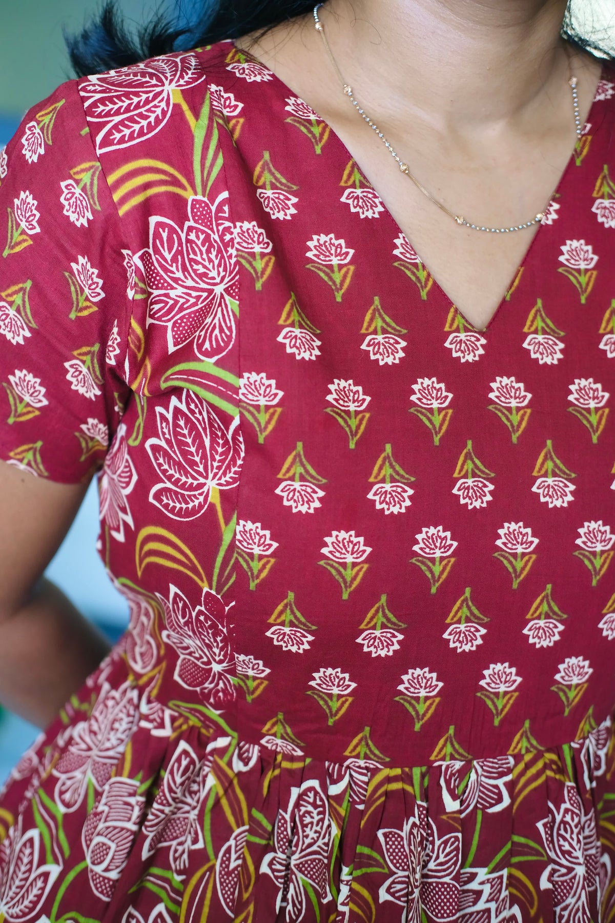 Close-up of the V-neck bodice of the red cotton midi nighty showing the detailed floral print and soft fabric texture.