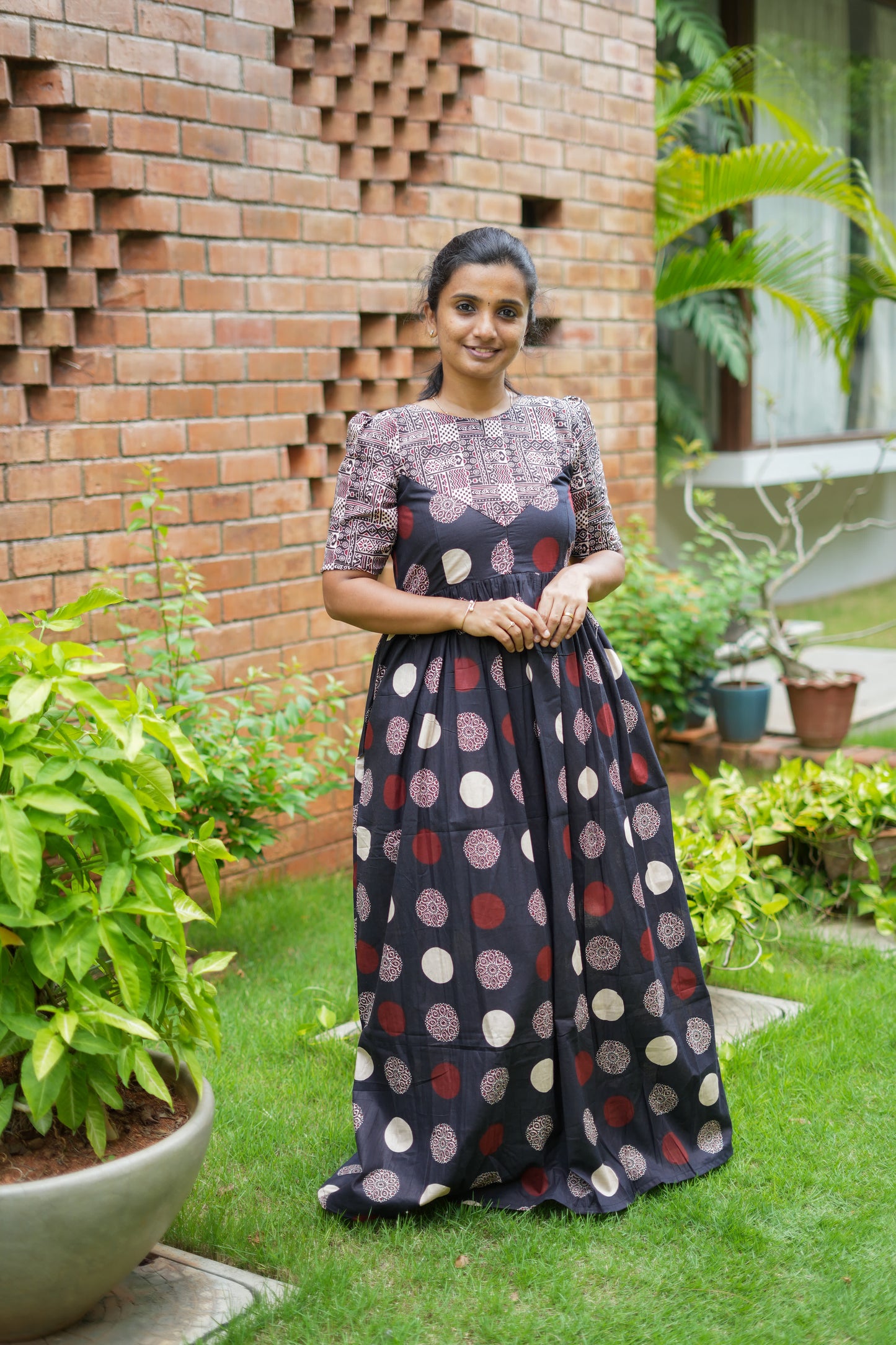 A woman wearing the Yamini black cotton maxi nighty with red and cream prints.
