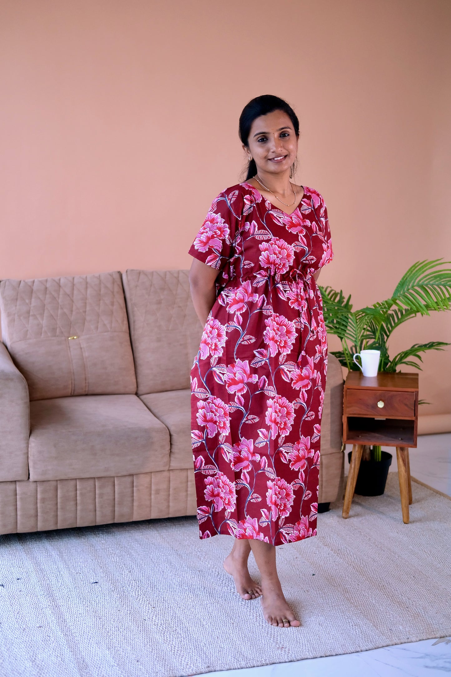 Midi-length cotton loungewear dress in maroon with a blooming pink floral pattern and a cinched drawstring waist.
